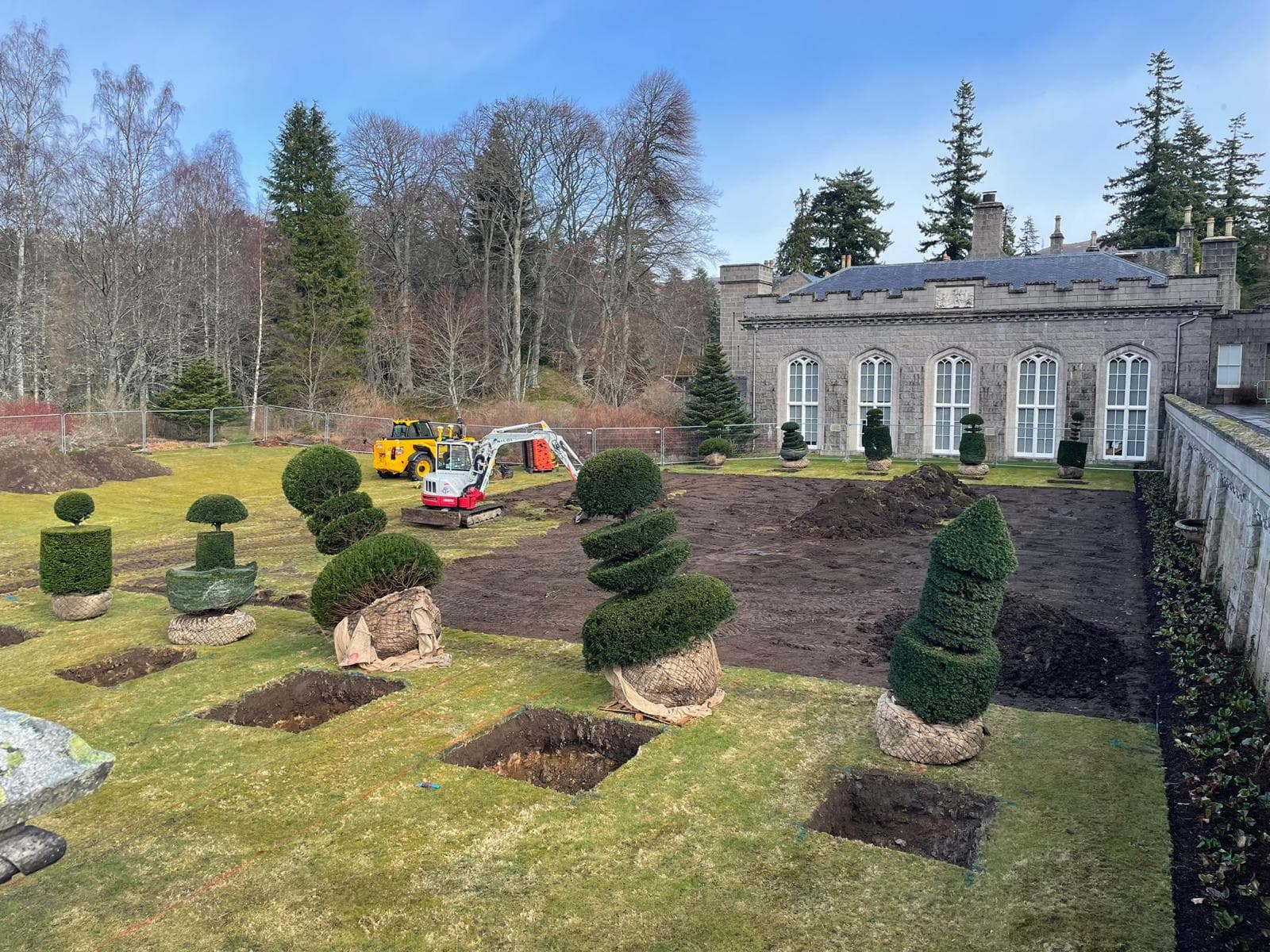 Topiary planting in progress at estate with mini digger